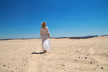 Girl in white dress walking in desert