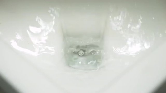 Men's restroom urinal flushed with clean water.