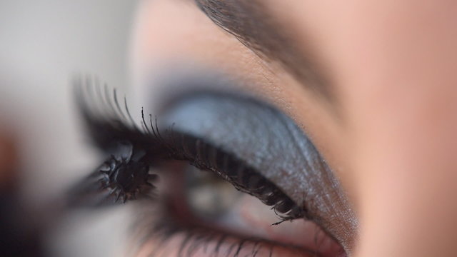 Woman applying mascara on eyelashes