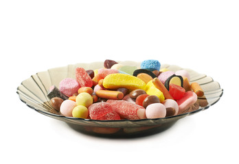 Glass plate full of candies isolated