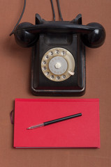 Retro style black russian dial telephone and red notebook