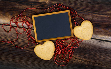Blackboard And Red Long Beads On Old Wooden Board. Happy Valentines Day. Romantic Composition.