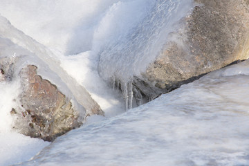 Fototapeta na wymiar Closeup of rocks along the coast of a lake covered with ice