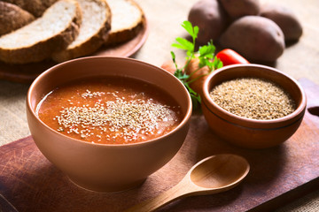 Cream of vegatable soup made of tomato, carrot, potato and parsley served in bowl and sprinkled with sesame seeds, photographed with natural light (Selective Focus, Focus in the middle of the soup)