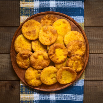 Overhead shot of traditional Chilean Sopaipilla fried pastry made with mashed pumpkin in the dough, served on wooden plate, photographed on wood with natural light