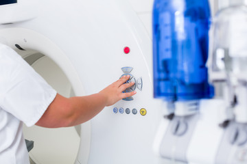 Röntgenschwester drückt Knopf am CT Tomograph in Klinik