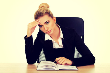 Tired businesswoman writing note by a desk