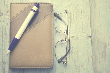 glasses, notebook and pen on the wooden table
