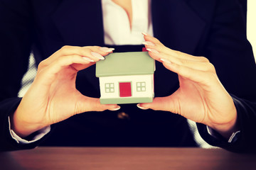 Businesswoman with small house behind the desk