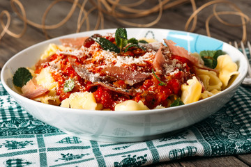 Tortellini with tomato sauce on wooden table.