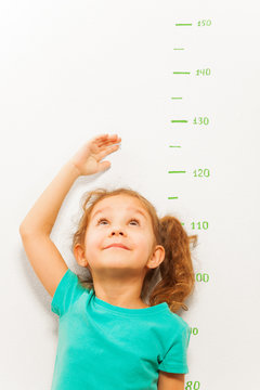 Girl measure height with hand looking up