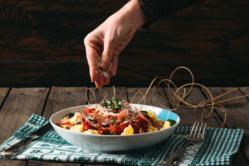Tortellini with tomato sauce on wooden table.