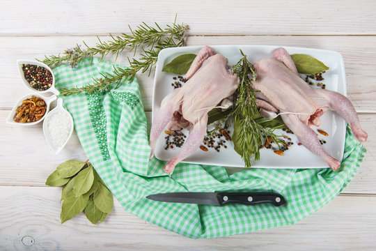 Picant&oacute;n o coquelet, pollo peque&ntilde;o crudo con hierbas y especias en la mesa de la cocina para una comida saludable