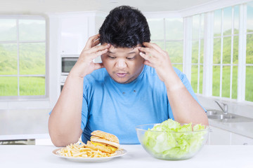 Confused man to choose hamburger or salad