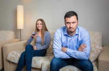 Portrait of couple sitting on sofa watching television. 