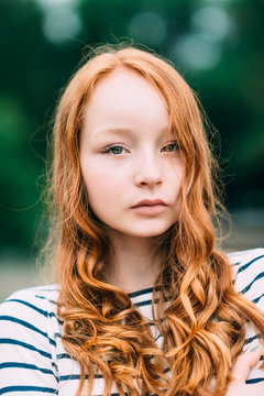 Outdoor portrait of a red-haired teenage girl. Adorable young redhead longhaired woman