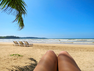 Beach view in selfie style with legs and palm leaf