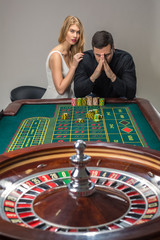 Men with women playing roulette at the casino. 