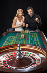 Man and woman cheering at roulette table in casino