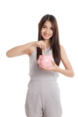 Beautiful young Asian woman with piggy bank and coin