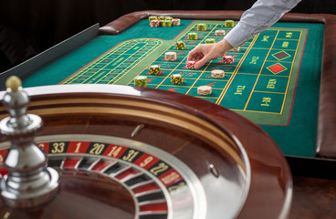 Roulette and piles of gambling chips on a green table. 