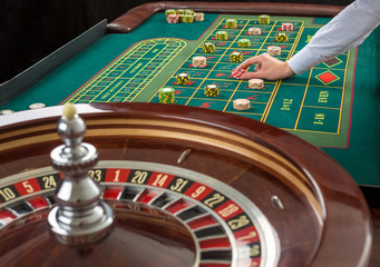 Roulette and piles of gambling chips on a green table. 
