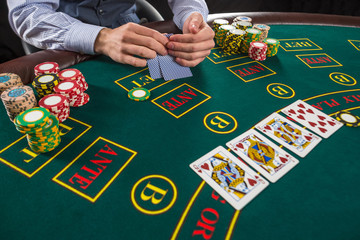 Closeup of poker player with playing cards and chips 