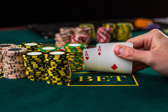 Male poker player lifting the corners of two cards aces 
