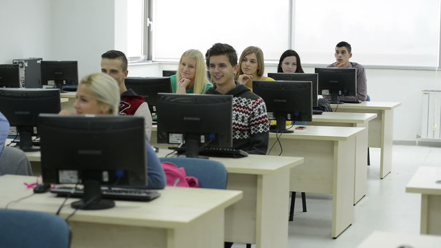 group of students with teacher in computer lab classrom learrning lessons,  get help and support