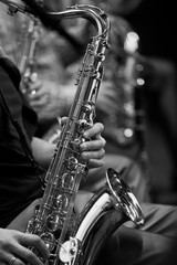 Obraz premium Saxophone in the hands of a musician in the orchestra in black and white 