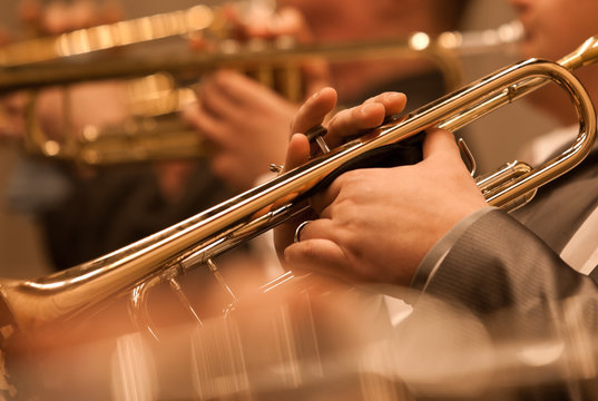 The trumpet in the hands of a musician in the orchestra closeup