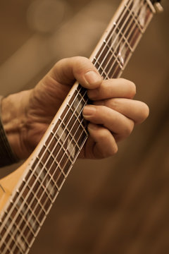  A man's hand on the strings of a guitar closeup