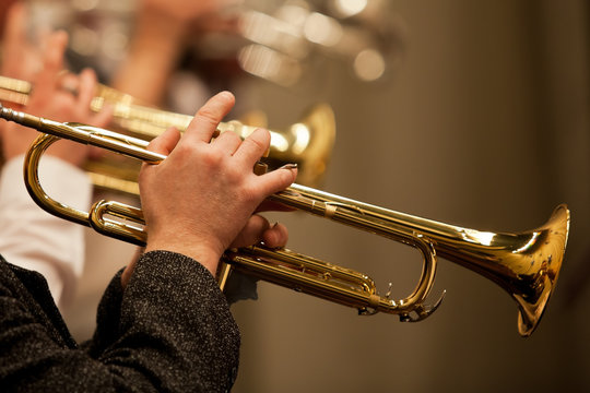 The trumpet in the hands of a musician in the orchestra closeup