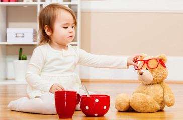 Toddler girl having tea time with her teddy bear