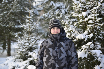 Fototapeta na wymiar teenage boy at a pine forest in winter