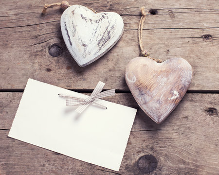 Two decorative  hearts  and empty tag on aged wooden background.