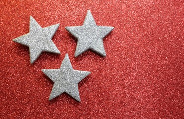 three silver stars on bright red glittery texture