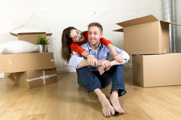 Fototapeta na wymiar young happy couple sitting on floor together celebrating moving in new flat house or apartment