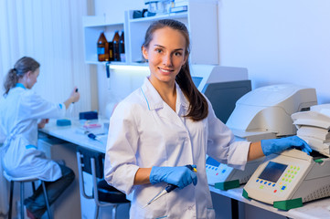 Woman researcher chemist in a white lab bathrobe  working with equipment in the modern laboratory