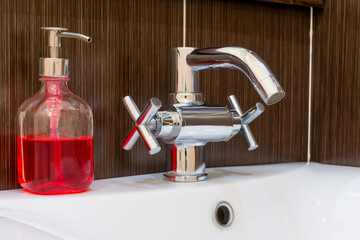 shiny faucet and soap dispenser in the bathroom close up