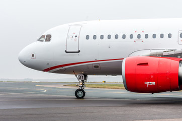 Fototapeta na wymiar White-red airplane taxiing in an airport
