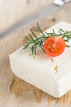 Schafskäse mit Rosmarin und Tomaten auf einem Holzbrett