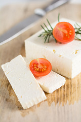 Schafskäse mit Rosmarin und Tomaten auf einem Holzbrett © Eddie