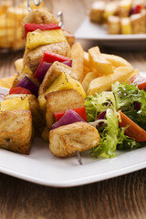 Grilled chicken skewers with pineapple, peppers and onions serve