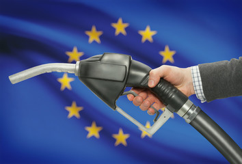 Fuel pump nozzle in hand with national flag on background - European Union - EU