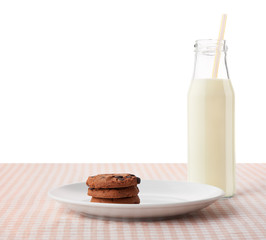 Chocolate chip cookies on white plate and bottle of milk