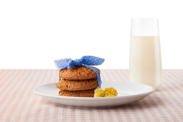 Oatmeal cookies and flowers on plate, glass of milk