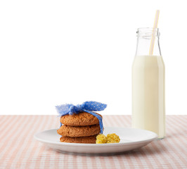 Oatmeal cookies and flowers on and bottle of milk