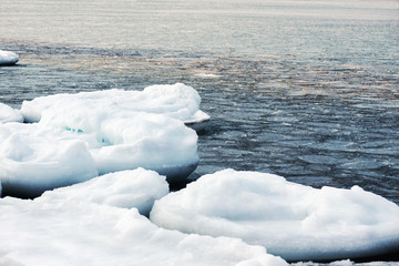 Natural sea ice blocks breaking up against shore. .