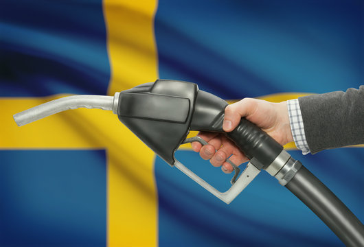 Fuel pump nozzle in hand with national flag on background - Sweden - Powered by Adobe